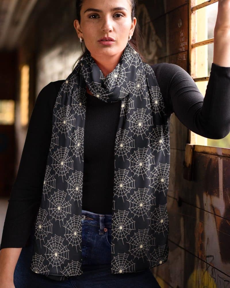 Woman wearing a black scarf with a cream-colored spiderweb pattern.