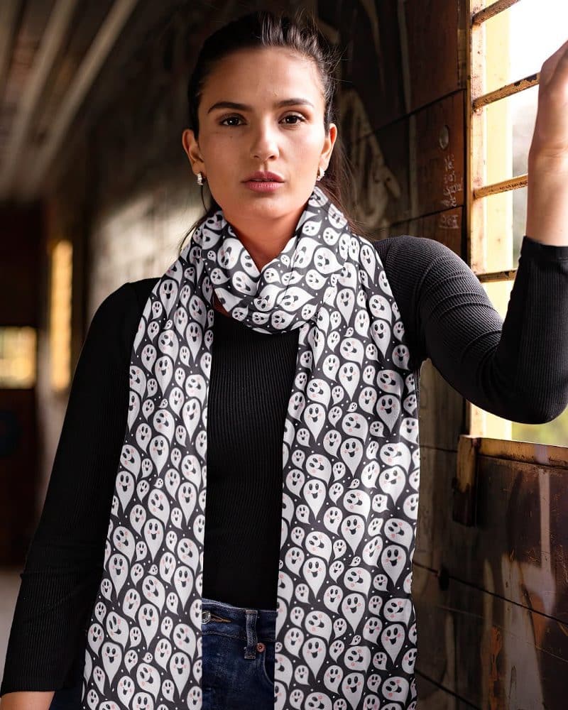 Woman wearing a black long-sleeved shirt and a black and white ghost patterned scarf.