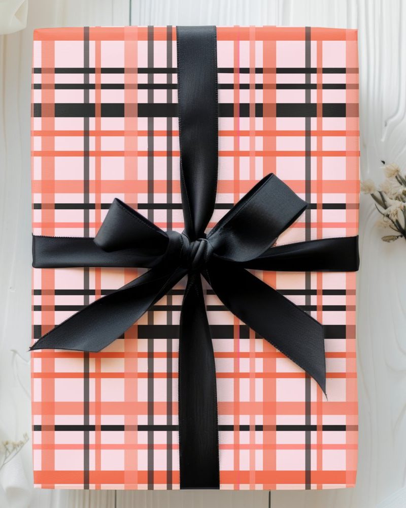 A gift box with a coral and black plaid pattern and a black ribbon.