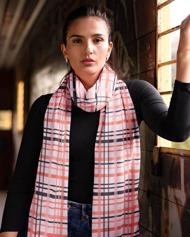 Woman wearing a peach and gray plaid scarf.