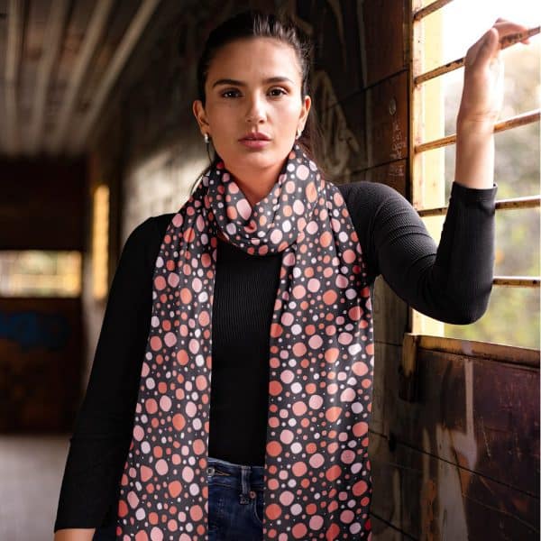 Woman Wearing A Dark Long-Sleeved Shirt And A Peach And Dark Gray Polka Dot Scarf.