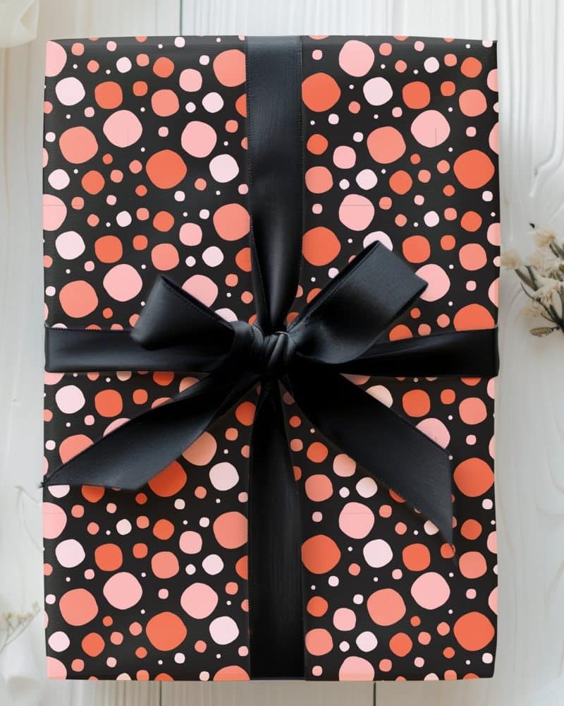 Gift wrapped in black and coral polka dot paper with a black ribbon.