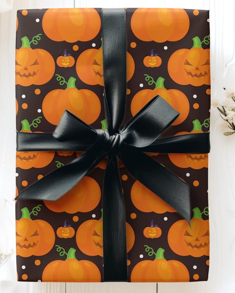Halloween gift wrapped in dark brown paper with a pattern of orange jack-o'-lantern pumpkins and a black ribbon.