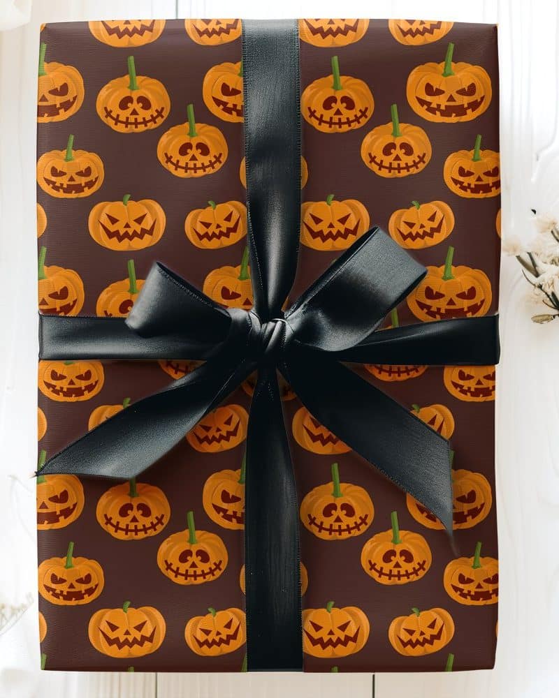 Gift wrapped in brown paper with a Halloween jack-o-lantern pattern and a black ribbon.