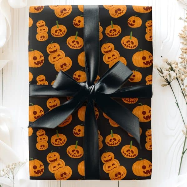 A Gift Wrapped In Black Halloween-Themed Wrapping Paper Featuring Orange Jack-O'-Lantern Faces, Tied With A Black Ribbon.