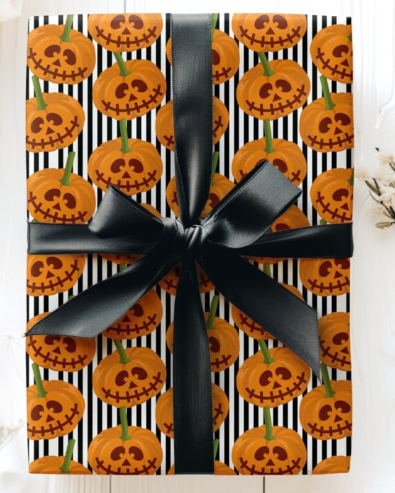 Halloween gift wrapped in black and white striped paper with a pattern of jack-o'-lantern faces and tied with a black ribbon.
