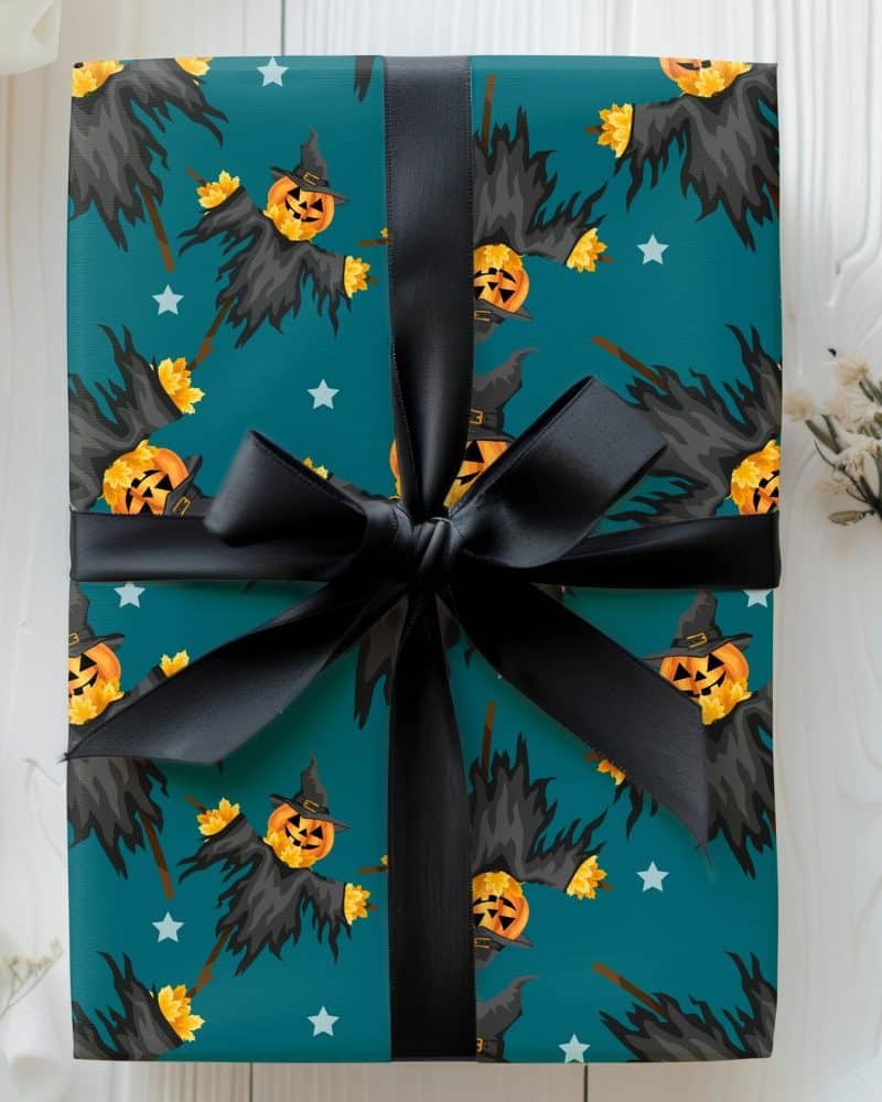 Teal Halloween gift wrapped with a black ribbon, featuring a pattern of scarecrows with jack-o'-lantern heads.
