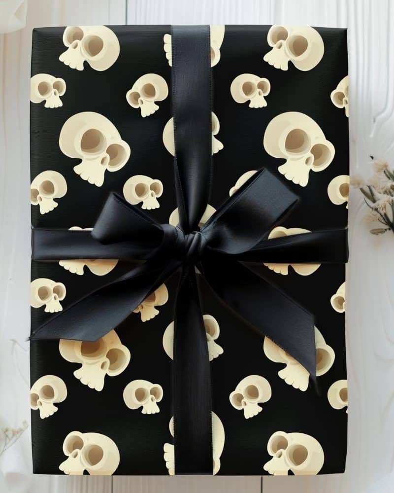 Gift wrapped in black paper with a repeating pattern of cartoon skulls and tied with a black ribbon.