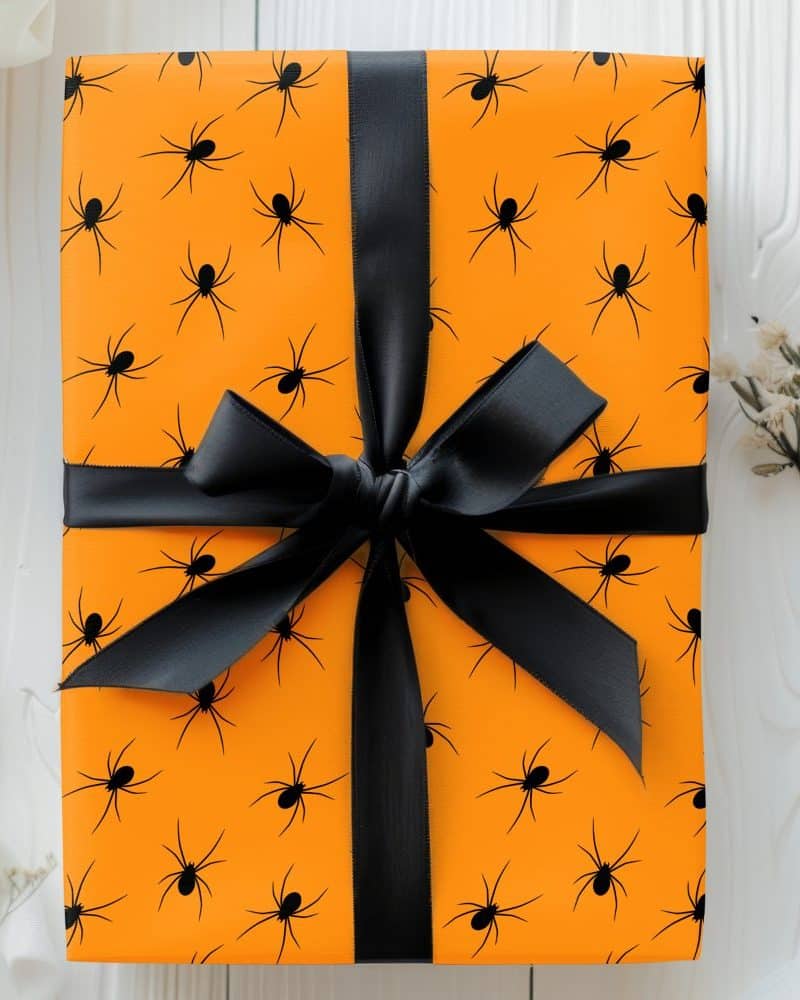 An orange gift box with black spiders and a black ribbon.