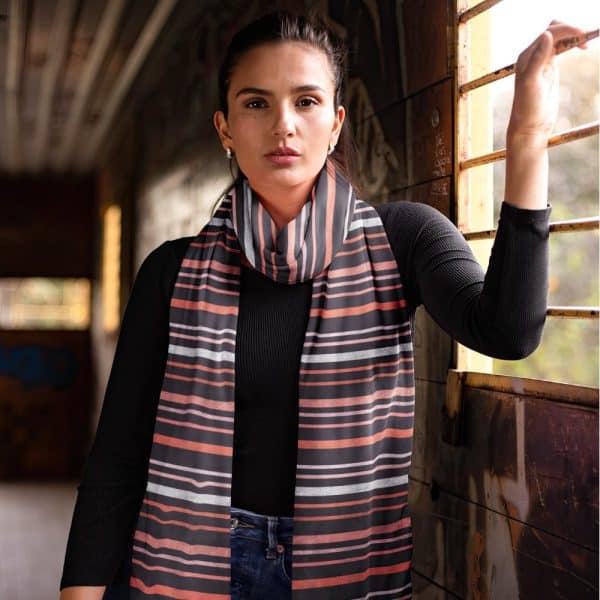 Woman Wearing A Horizontally Striped Scarf In Coral, Gray, And Black.