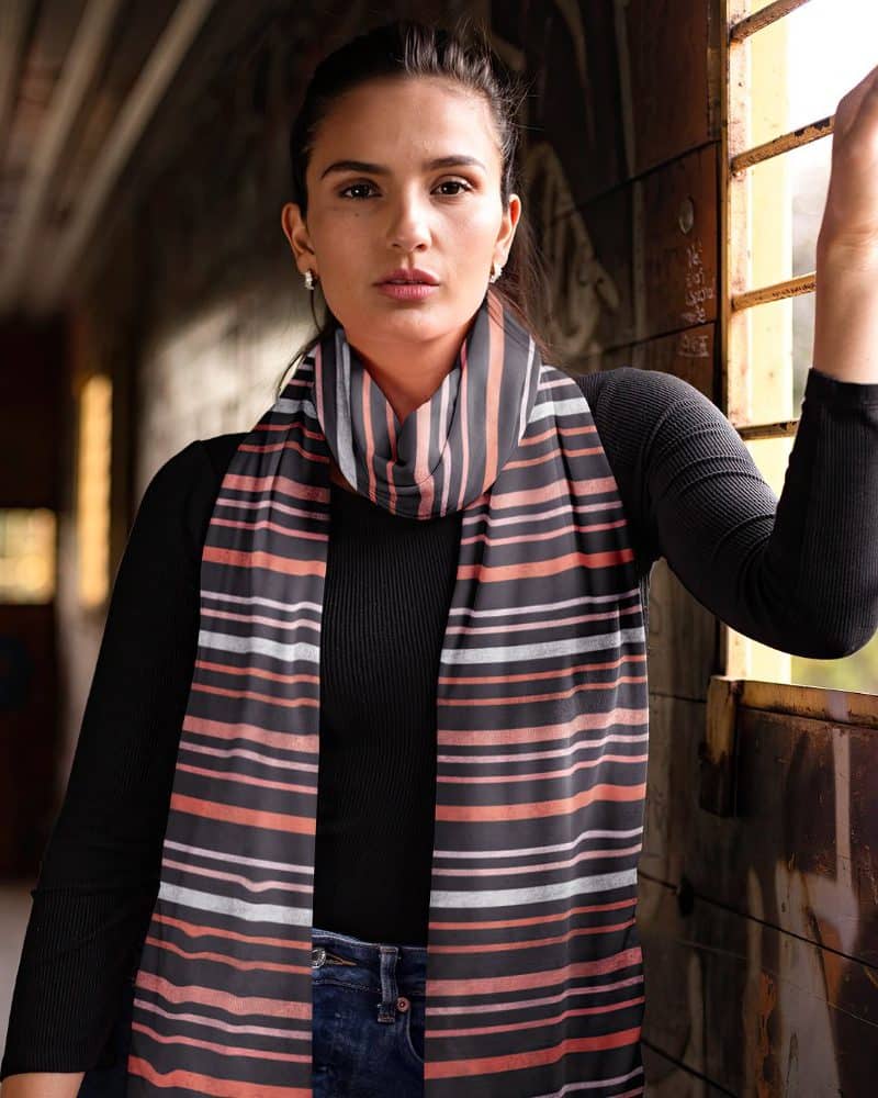 Woman wearing a horizontally striped scarf in coral, gray, and black.