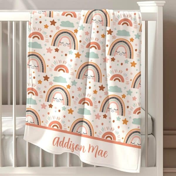 Personalized Baby Blanket With A Pattern Of Pastel Rainbows, Stars, And Clouds. The Name Addison Mae Is Embroidered At The Bottom.