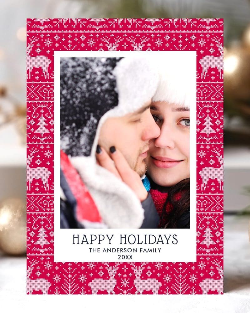 Holiday card featuring a close-up photo of a couple embracing, framed by a festive red and white knit pattern.