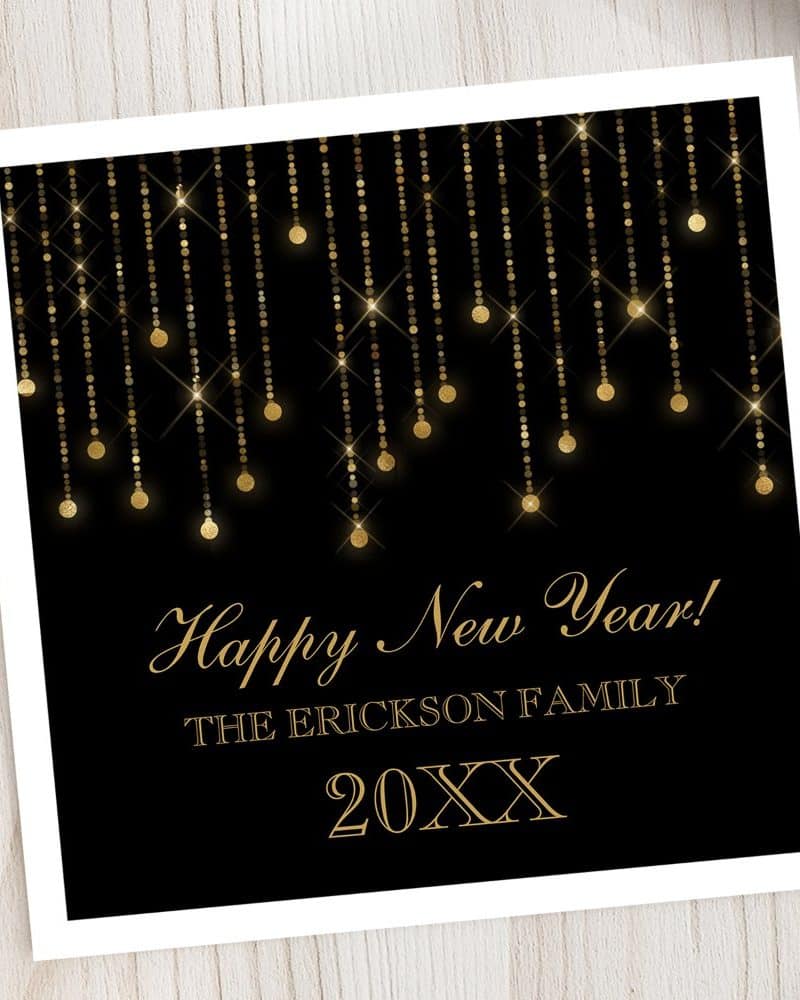 Black and gold Happy New Year card featuring glittering gold strands of lights.