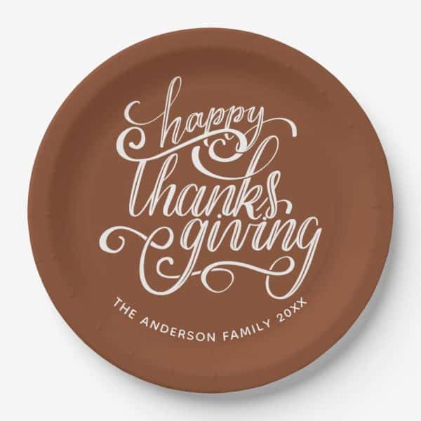 Brown Paper Plate With White Cursive Lettering That Says Happy Thanksgiving And The Anderson Family 20Xx.