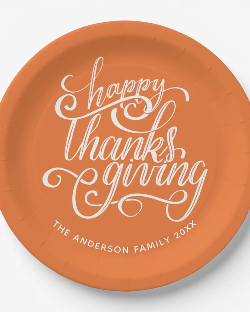 Orange paper plate with a stylized Happy Thanksgiving message.