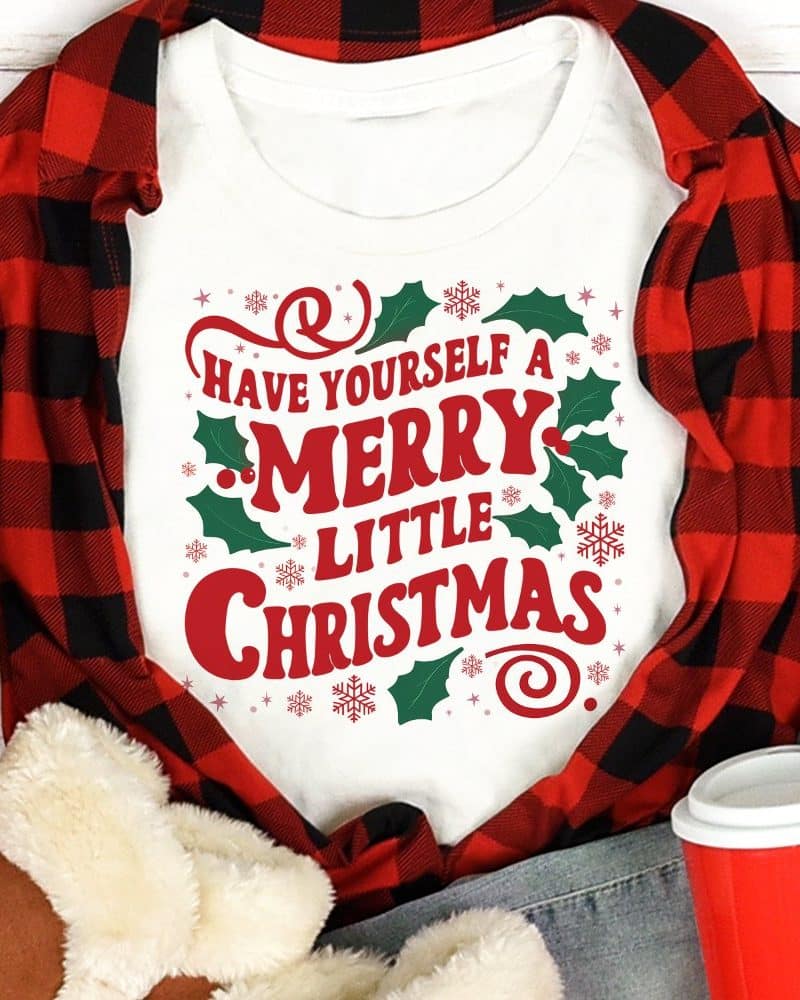 White shirt with red and green Christmas design that says Have Yourself a Merry Little Christmas.