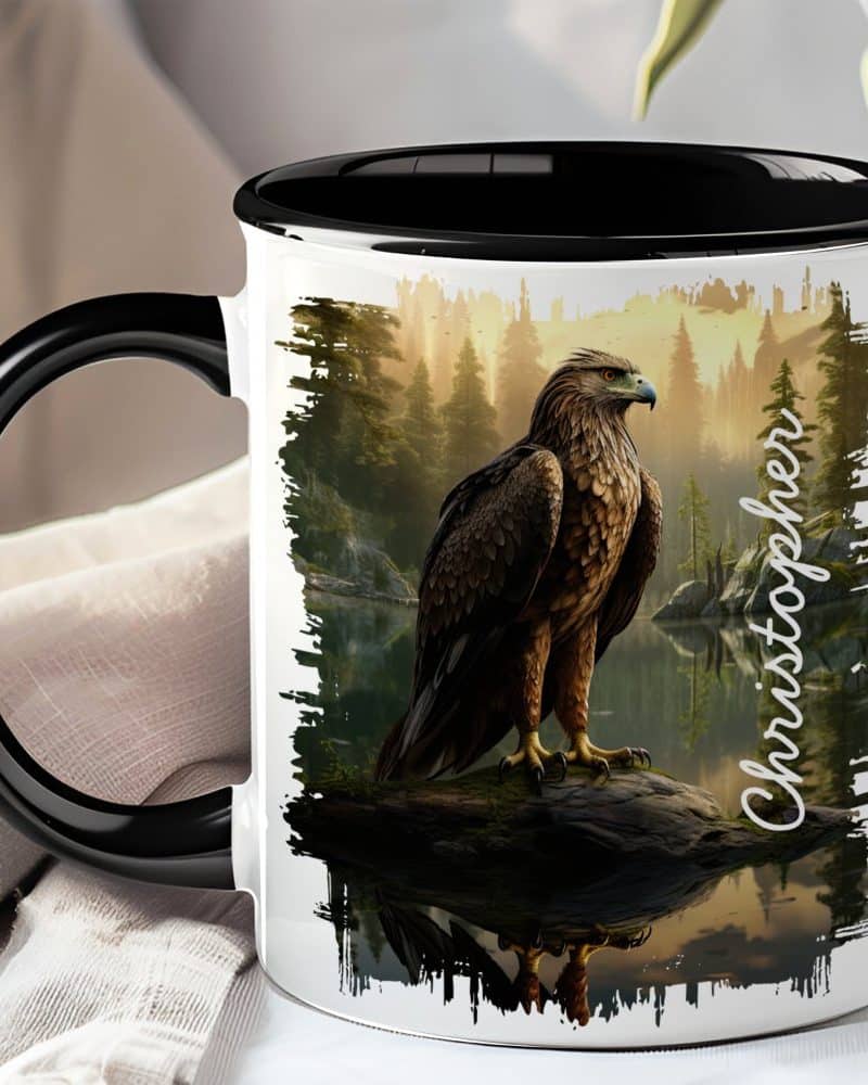 Black-handled mug with a personalized design featuring an eagle perched on a rock by a lake in a forest.
