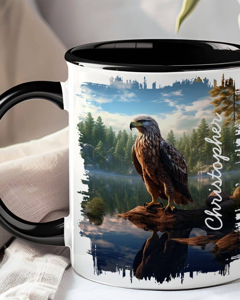 Black-handled mug with a graphic of an eagle perched on a log by a lake in a forest.