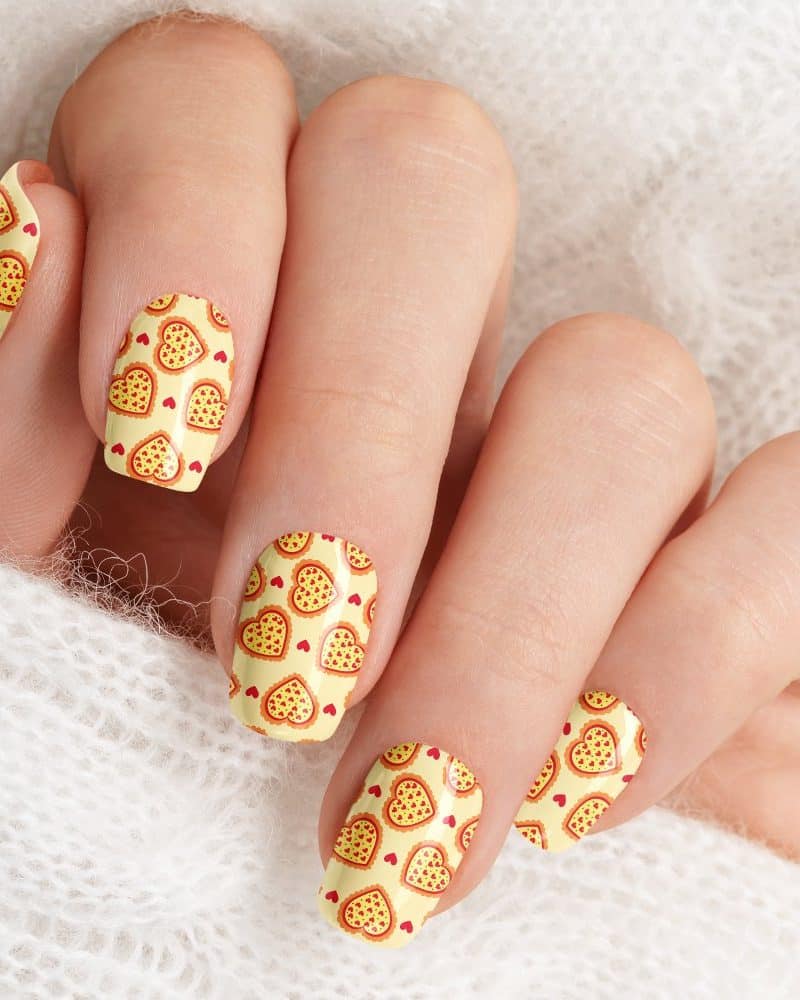 Close-up of fingernails with pizza-shaped heart nail art.
