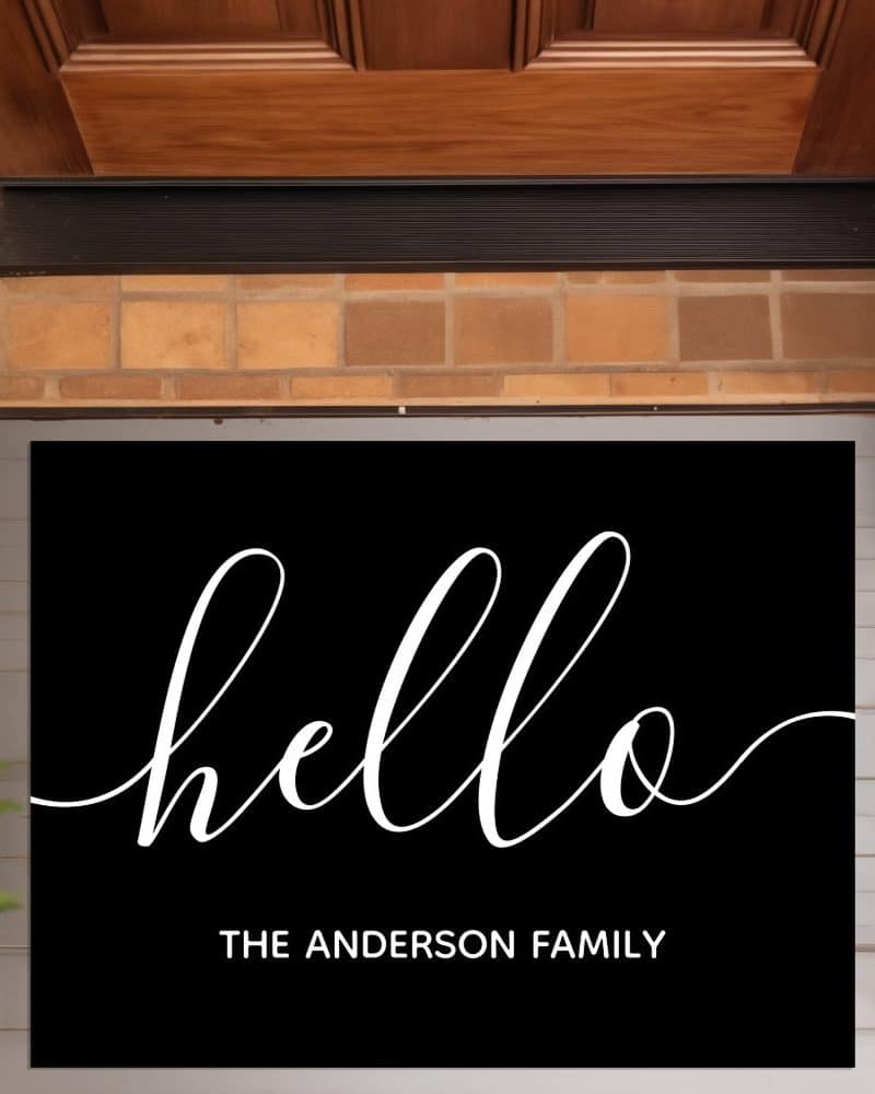 Black welcome mat with white script lettering that says hello and The Anderson Family below.