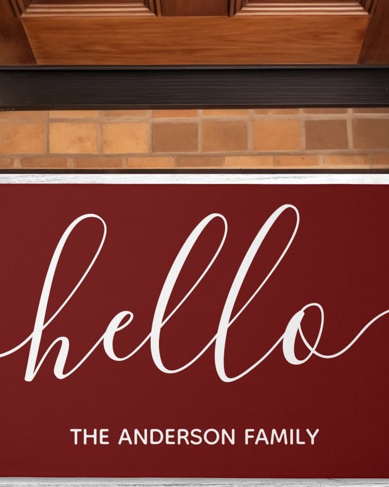 Burgundy welcome mat with the word hello in a white script font and The Anderson Family written below.