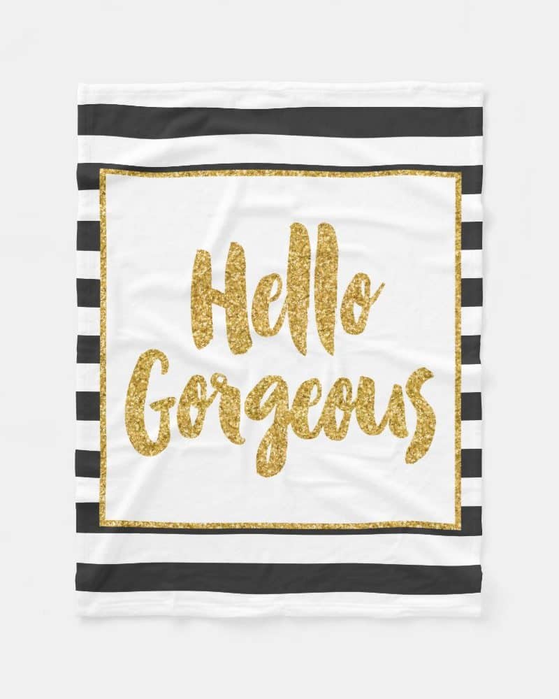 White throw blanket with black stripes and gold glitter lettering that says Hello Gorgeous.