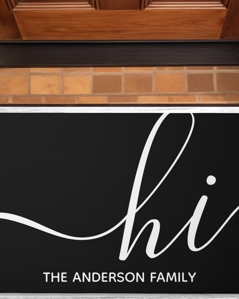 Black welcome mat with white script lettering that says hi and The Anderson Family below.