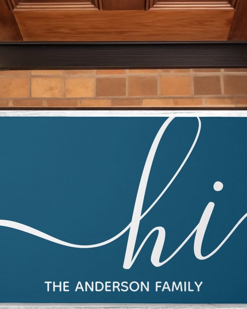 Teal doormat with the word hi in a stylized white script font and The Anderson Family below.