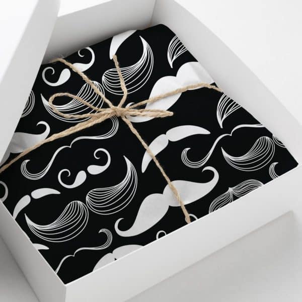 A Gift Box Containing A Black And White Present Wrapped In Paper With A Repeating Pattern Of Mustaches. The Package Is Tied With Twine.