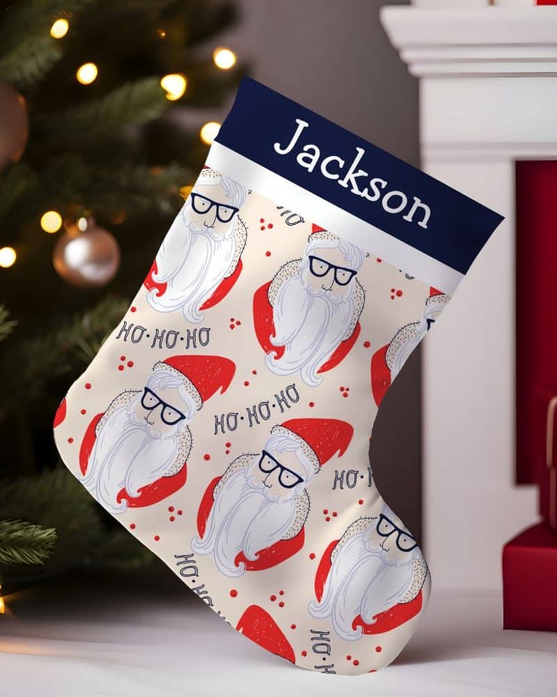 Personalized Christmas stocking with a cream background featuring a repeating pattern of hip Santa Clauses wearing glasses and the name Jackson at the top.