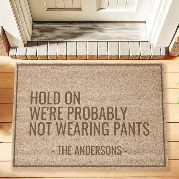 Beige Doormat With The Text Hold On We'Re Probably Not Wearing Pants And The Anderson Family Name.