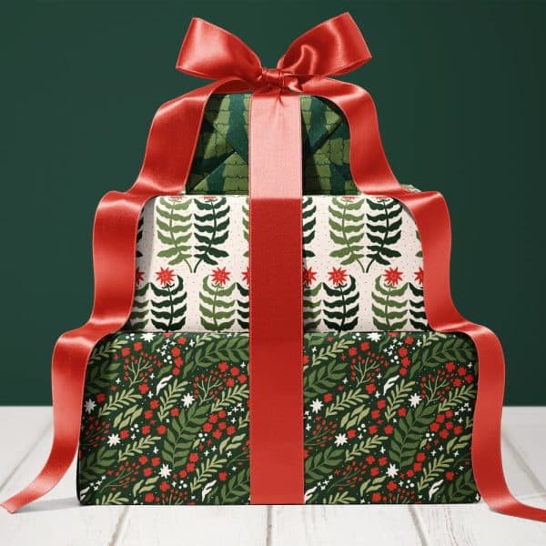 Stack Of Three Christmas Presents Wrapped In Festive Green And Red Patterned Paper, Tied With A Large Red Ribbon.