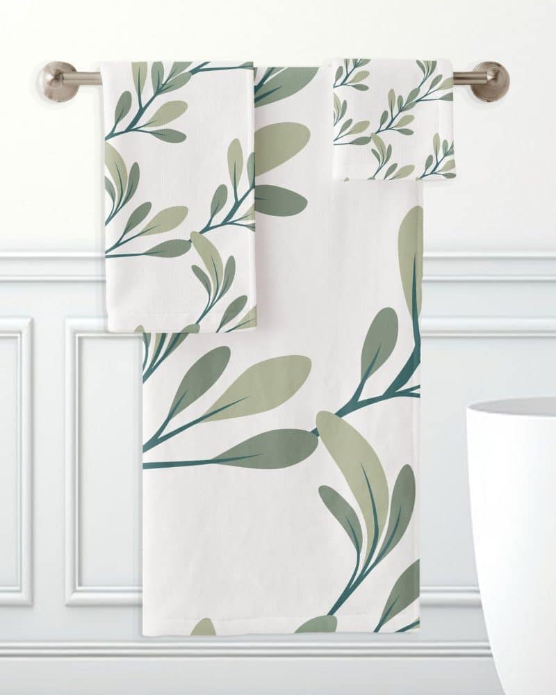 A bath towel set with a leaf pattern in shades of green on a white background.