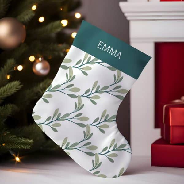 Personalized Christmas Stocking With A Teal Cuff And A White Body Featuring A Repeating Leaf Pattern. The Name Emma Is On The Cuff.