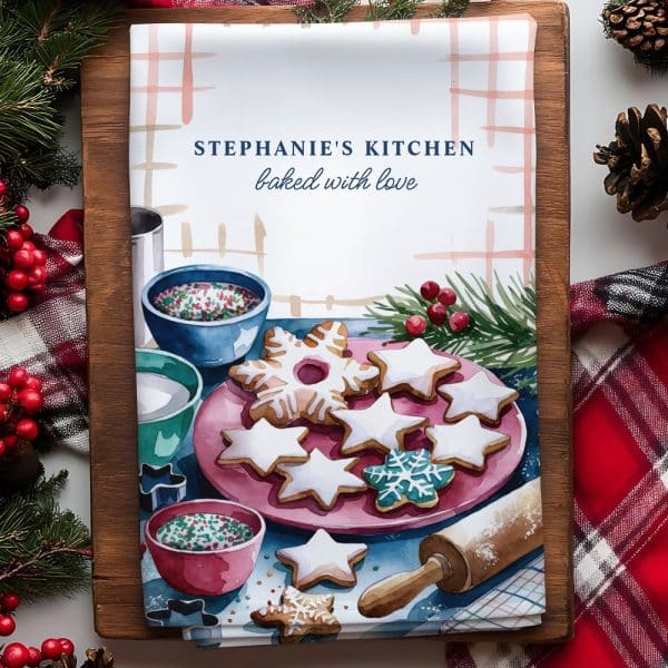 A Kitchen Towel Featuring A Watercolor Painting Of Star-Shaped And Snowflake-Shaped Christmas Cookies On A Pink Plate.