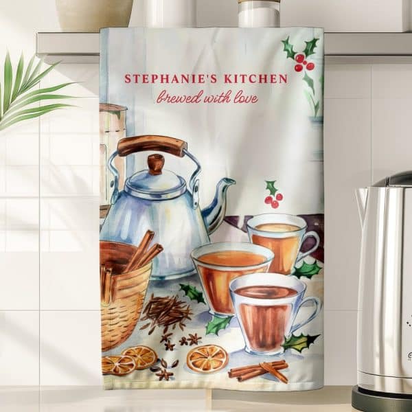 Kitchen Tea Towel With A Watercolor Illustration Of A Teapot And Mugs Of Tea, Surrounded By Cinnamon Sticks, Orange Slices, And Spices. The Text &Quot;Stephanie'S Kitchen Brewed With Love&Quot; Is Also Present.