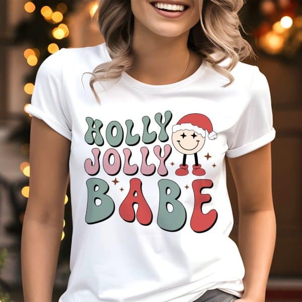 White T-Shirt With A Retro Design Reading Holly Jolly Babe And A Small Illustration Of A Smiling Character Wearing A Santa Hat.
