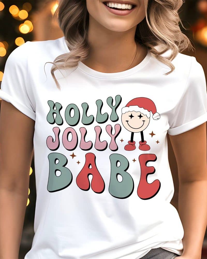 White t-shirt with a retro design reading Holly Jolly Babe and a small illustration of a smiling character wearing a Santa hat.