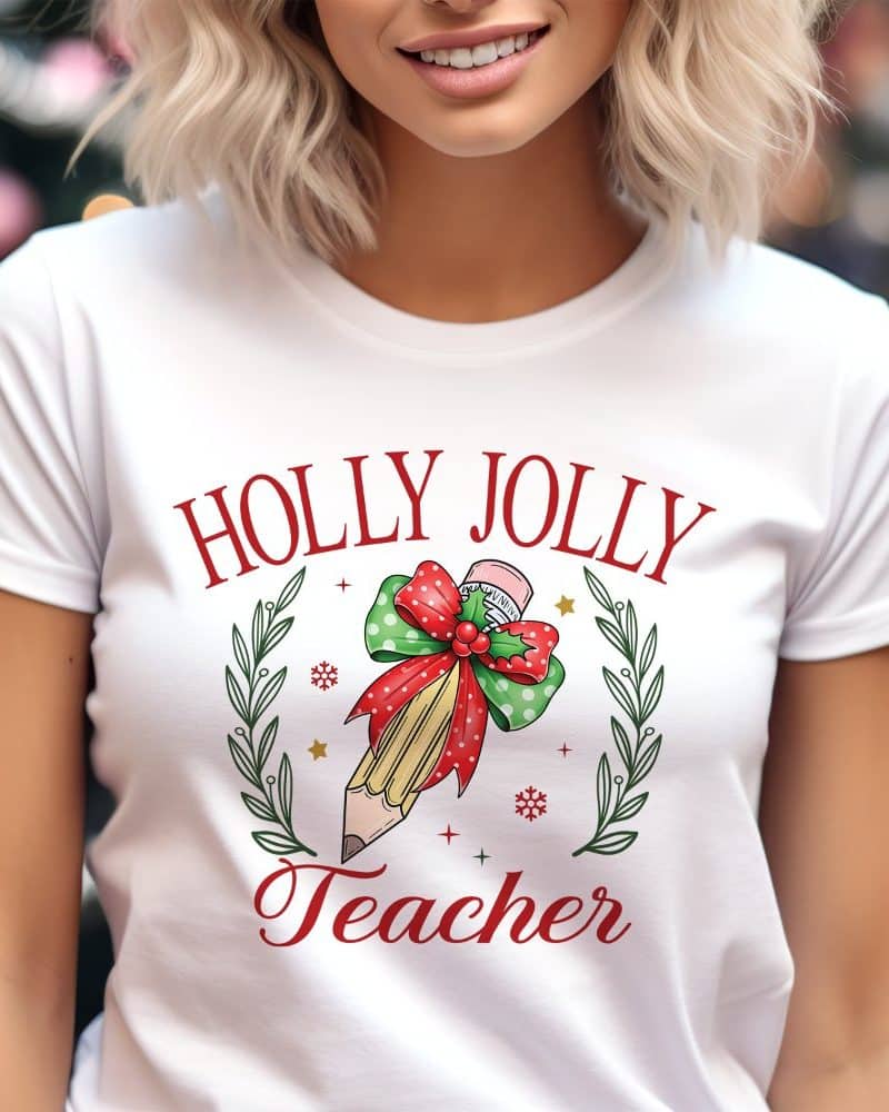 White t-shirt with a Christmas design: Holly Jolly Teacher. A pencil is adorned with a festive bow and greenery.