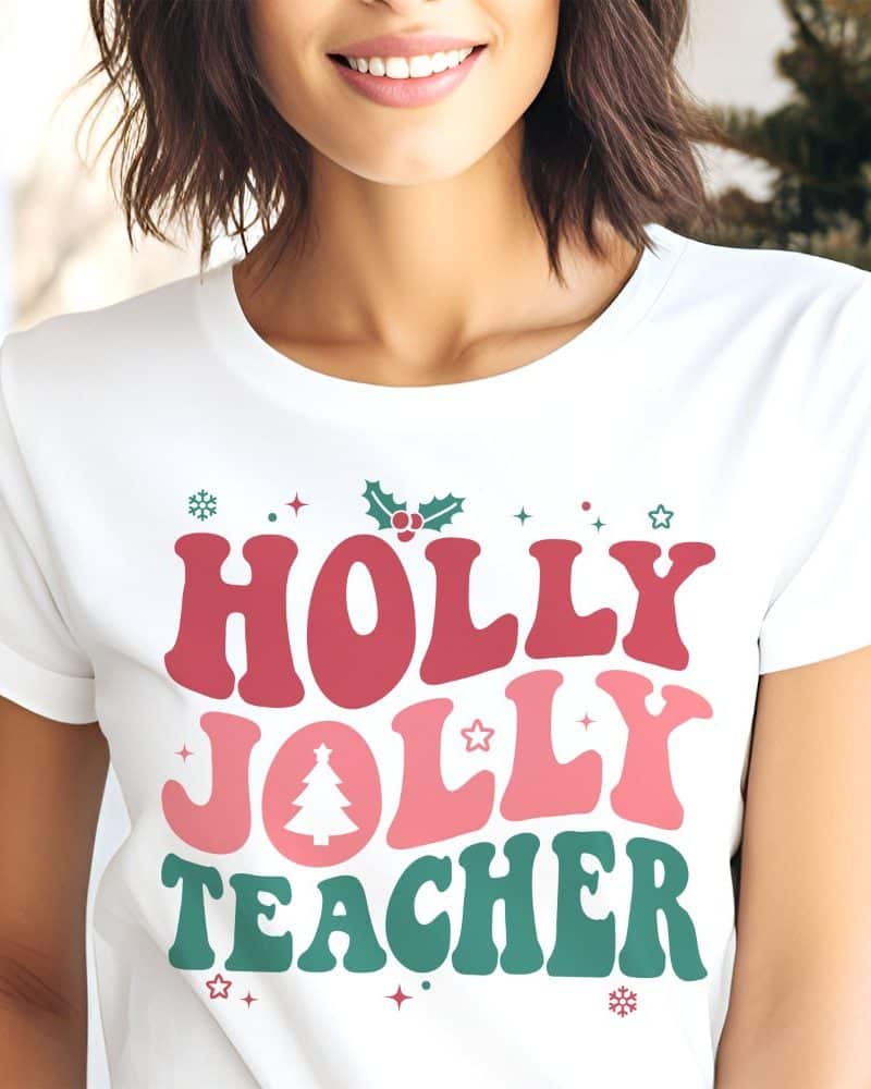 Woman wearing a white t-shirt with a festive design that says Holly Jolly Teacher.