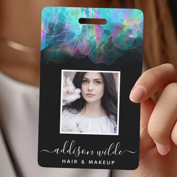 Black Id Card With A Teal And Purple Watercolor Design At The Top, A Headshot Of A Woman, And The Name Addison Wilde, Hair &Amp; Makeup, At The Bottom.