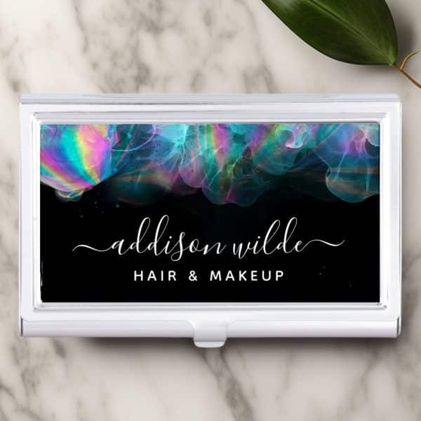 A White Business Card Holder Displays A Black Background With Iridescent Teal, Pink, And Purple Abstract Designs. The Name Addison Wilde, Hair &Amp; Makeup Is Written In White Script.