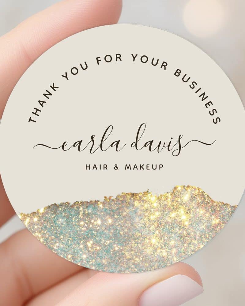 Round business card featuring Carla Davis Hair & Makeup. The card has a sparkly gold and teal design at the bottom.