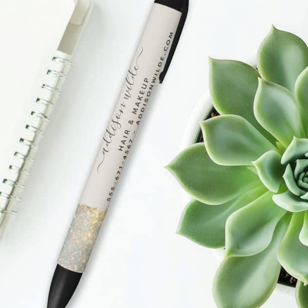 A Pen With Gold Glitter And The Name Addison Wilde, Hair And Makeup Artist, And Contact Information Printed On It.