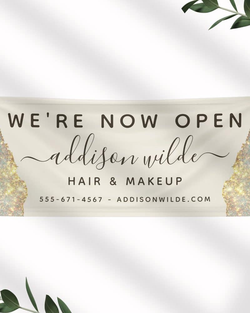 Grand opening banner for Addison Wilde Hair & Makeup. The banner features a cream background with gold glitter accents.