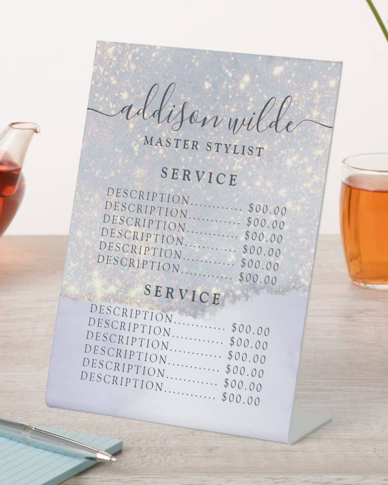 A freestanding price list for Addison Wilde, Master Stylist, shows services and prices on a sparkly light-blue background.
