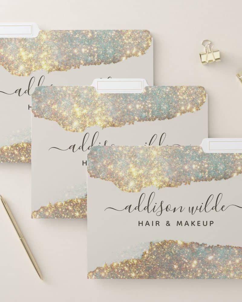 Three file folders with a sparkly gold and beige design and the name Addison Wilde Hair & Makeup.