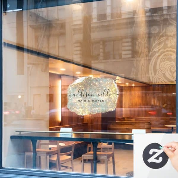 A Salon Logo On A Storefront Window. The Logo Is A Sparkly, Light-Colored, Abstract Shape With The Words Addison Wilde Hair &Amp; Makeup In Elegant Script.