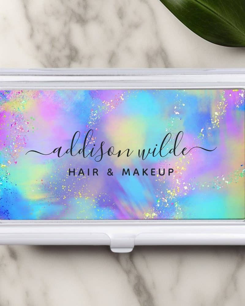Silver business card holder with a pastel rainbow design and the name Addison Wilde, Hair & Makeup.